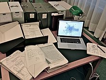 A laptop computer next to archival materials