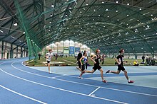 Indoor track and field facility with a group of runners circling the track