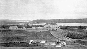 Внешний вид Индийской индустриальной школы Qu'Appelle в Лебре, округ Ассинибойя, гр. 1885. На переднем плане видны окрестности и палатки.