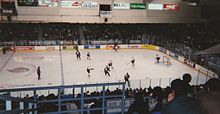 men on skates playin ice hockey up in a arena