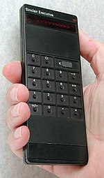 Nigra rektangula kalkulilo estanta tenita en la dekstra mano de persono.