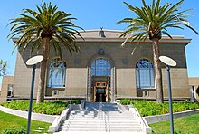 Exterior of the Richmond Branch Library. Entrance stairway is flanked by two large palm trees.