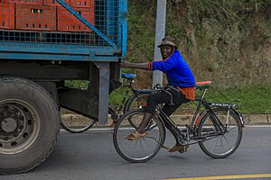 Ein Fahrradfahrer lässt sich von einem Lastwagen die Straße bergauf ziehen