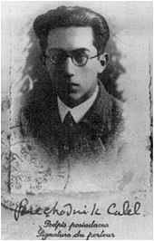 Photographie en noir et blanc d’un jeune homme brun à lunettes.