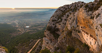 Vista do pôr do sol com a Capela da Virgem da Penha (Ermita de la Virgen de la Peña) em primeiro plano e a vila de Aniés ao fundo, província de Huesca, Espanha. As partes mais antigas do santuário são de origem românica e datam do século XIII. O único acesso para a capela é através de uma trilha de montanha, sinuosa e íngreme. (definição 7 256 × 3 800)