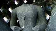 A headless Buddha statue inside a stupa.