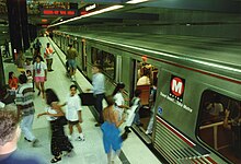 Crowds of people are getting on and off on a train stopped at an underground station