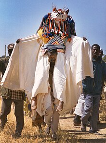 Funerary dance ritual. A blacksmith carries the dressed body. Kapsiki people, North Cameroon. The corpse is dressed and carried by a blacksmith. Kapsiki.jpg