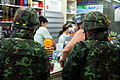 Soldiers and a helmeted journalist buy water and food, Silom Road