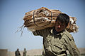 An Afghan Local Police officer carries a bundle of empty sandbags during a checkpoint construction project