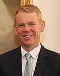 A smiling man wearing a dark business suit and tie