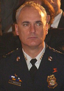 Bealefeld, a man with gray receded hair, wearing his uniform, suit jacket, and black tie, at an event.