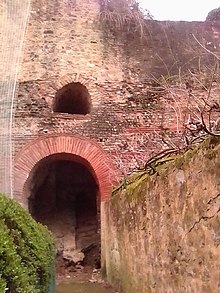 Vue d'un mur avec deux ouvertures de taille différente superposées et pourvues d'un arc en briques