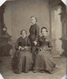 three women posing together for a portrait in 1876. the two on the left and right - Elizabeth Ann Whitney and Eliza R. Snow, respectively - are sitting, while the one in the middle - Emmeline B. Wells - stands