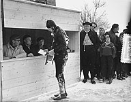 Een schaatser met een stempelkaart bij een stempelhokje voor controle in Hindeloopen. Elfstedentocht 1956.