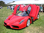 Izsmalcināts sarkans sporta auto, skatoties no priekšpuses, ar paceltām spārnu durvīm