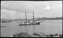 Photographie en noir et blanc dun navire entrant dans un port.