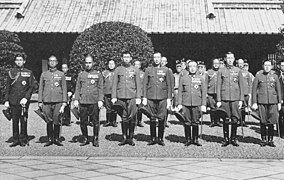 Photo d'un groupe d'hommes en uniforme. Ils sont alignés et posent devant un bâtiment.