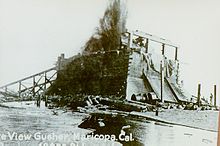 A timber containment box was pulled over the gusher with heavy cables, soon destroyed by the oil's pressure