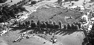A black-and-white aerial shot of Knebworth Estate - a field filled with people all facing a large stage