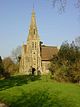 A short stone church with a tall narrow tower and spire