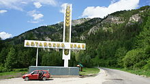 Grand monument avec un épi de blé sur le bas côté d'une route dans une vallée.