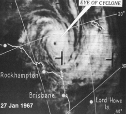 Satellite image of a small tropical cyclone near the northeastern coast of Australia. A long band of clouds is seen extending to the southeast.