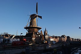 Photographie en couleurs d'un moulin à vent entouré d'un paysage urbain en travaux.