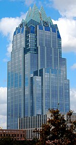 Ground view of the Frost Bank Tower; the tower has the appearance of an owl; the building has multiple setbacks; there is a cyan colored crown on the top of the building.