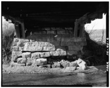 View of abutment from under bridge: Detail of both double Burr Arches beating on stone abutment (Note damage to abutment)