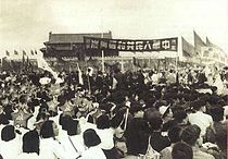 Guru dan para siswa SMA 4 Beijing menghadiri proklamasi berdirinya Republik Rakyat Tiongkok di Lapangan Tiananmen, 1 Oktober 1949, sambil membawa spanduk bertuliskan "中華人民共和國萬歲" (Hidup Republik Rakyat Tiongkok)