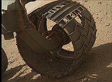 Close-up view of a well-worn wheel on the surface, which also shows the Morse code pattern for JPL. MarsCuriosityRover-WornWheel-20140218.jpg