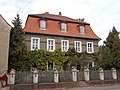 Wohnhaus mit zwei Seitengebäuden, Vorgarten und Einfriedung