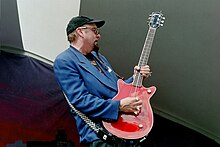 photo d'un homme jouant d'une guitare rouge.