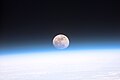 Original caption from NASA: "S103-E-5037 (21 December 1999)--- Astronauts aboard the Space Shuttle Discovery recorded this rarely seen phenomenon of the full Moon partially obscured by the atmosphere of Earth. The image was recorded with an electronic still camera at 15:15:15 GMT, Dec. 21, 1999.".