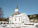 Foto einer weiß gestrichenen Holzkirche in verschneiter Umgebung