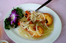 Photo of split lobster claw on plate, covered by onions