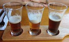 A beer flight of three beers, on a wooden beer paddle, served by a bar in Brisbane, Australia Story Bridge Hotel 06.JPG