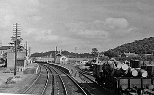 Abermule station in 1953, looking north-east towards Welshpool. There are few changes since 1921. The station buildings are on the up platform to the left, the signal box on the down platform to the right.