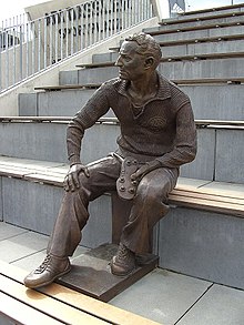 Statue de bronze assise sur les tribunes en bois d'un stade
