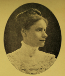 B&W portrait photo of a woman with her hair in an up-do, wearing a white blouse.