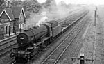A British Railways train, hauled by ex-War Department 2-8-0 No. 90035, moves empty flatcars past Barnetby station in 1961