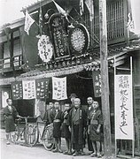 新築落成の記念大売り出し（1912年（明治45年））。カンカン帽をかぶっているのが六代目の主人[4]。