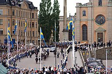 The procession carriage passing through a large crowd of people on Slottsbacken KortegenBacken03.jpg