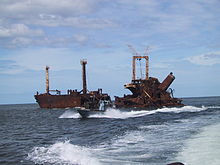 A fast attack boat of the rebel LTTE in Sri Lanka in 2003 passes the hulk of an LTTE supply ship that had been sunk by government aircraft, Sri Lankan Civil War (1983-2009). LTTE Sea Tigers attack vessel by sunken SL freighter.JPG