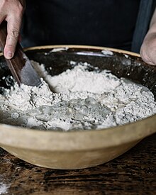Sourdough starter being stirred into flour to produce sourdough: the recipe calls for some sourdough left over from the last time the same recipe was made. Mixing Sourdough starter into the flour.jpg