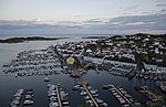 Foto einer an der Küste gelegenen Siedlung mit vielen weißen Gebäuden und Booten im Hafen