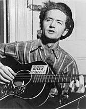 American singer-songwriter and anti-fascist Woody Guthrie and his guitar labelled "This machine kills fascists" Woody Guthrie NYWTS.jpg