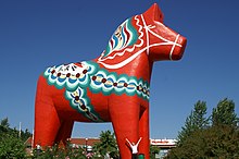 statue monumentale de cheval peinte en rouge avec crinière et selle ornées de motifs bleutés