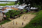 Children play football on a dirt pitch near tin-roofed houses on the bank of the Itaya River.